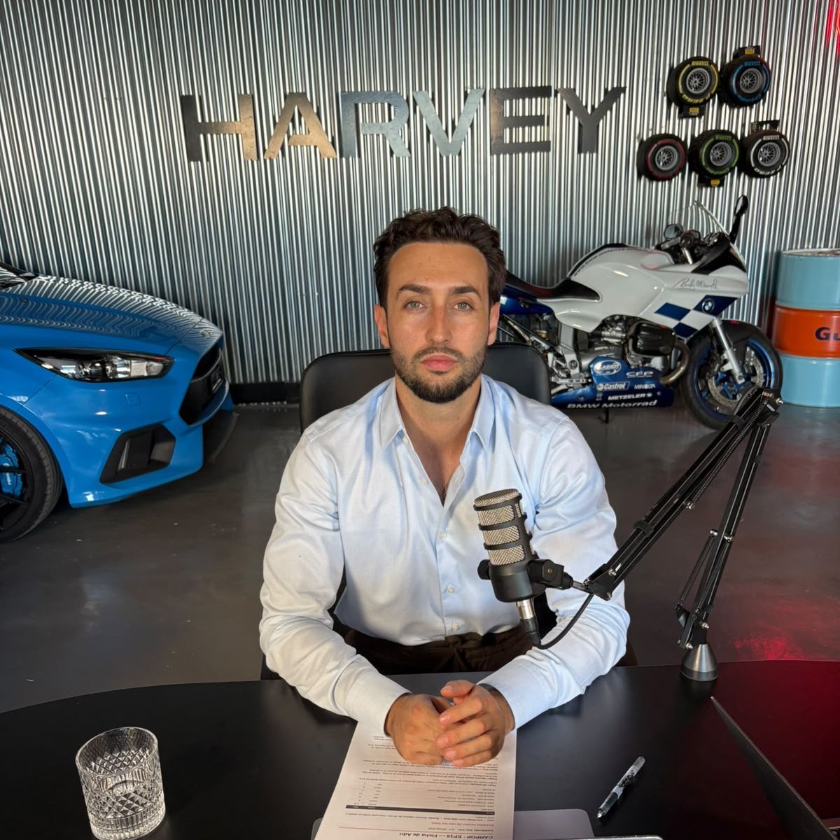 Adrià Méndez en el estudio de Harvey, con el logo HARVEY, el BMW M azul y la moto BMW al fondo